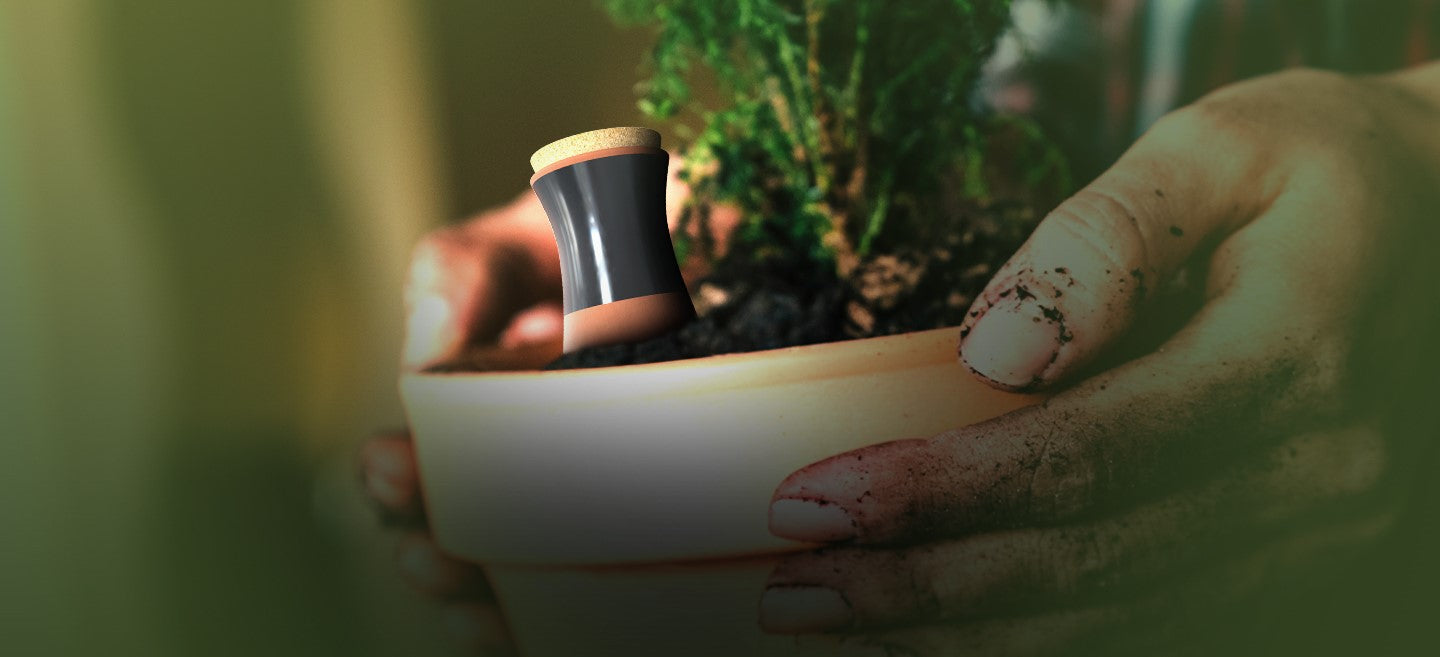 Smarti Living Olla partially inserted in a potted plant, with hands covered in soil, representing sustainable and efficient plant watering solutions.